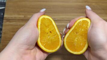 Squeezing out the fresh orange. A picture of a person's hand squeezing orange juice. Hand squeezing half fresh oranges on the orange press with pulp. hand holding fresh raw citrus. video