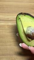 avocado on a wooden background in the hand of a young girl avocado bone health benefits useful vegetable fats proper nutrition diet there is space for text video