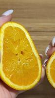 Squeezing out the fresh orange. A picture of a person's hand squeezing orange juice. Hand squeezing half fresh oranges on the orange press with pulp. hand holding fresh raw citrus. video