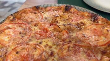 Freshly prepared pizza with tomatoes, salami, pickles, mushrooms and cheese. Macro shot in motion video