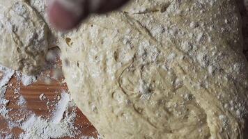 Soft, freshly kneaded dough covered in flour resting on a rustic wooden surface, with visible air bubbles and texture, preparing for baking in a cozy home kitchen setting video