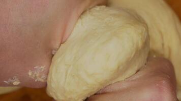 Close-up of hands kneading soft dough, fingers covered in flour, pressing and folding the dough, warm kitchen lighting enhances texture, creating a cozy and artisanal home baking atmosphere video