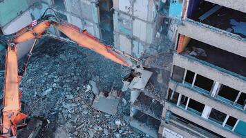Excavator crashing floors of an old building and dusty debris falling down. Disassembling of collapsed structures. View from above. video