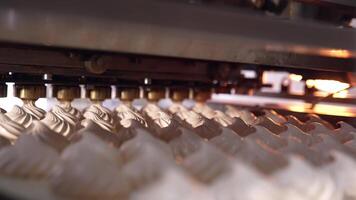 A number of freshly-made creamy marshmallows moving on the conveyor line. New marshmallows being squeezed at the backdrop. Close view. video