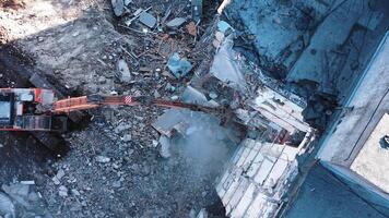 Long claw of an excavator destroys the concrete parts of the building. Demolition of premises after an earthquake. Up view of excavators working with ruins of demolished buildings. video