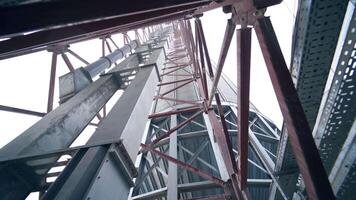 Pipes and supports at the grain-drying complex. High steel constructions at the backdrop of sky. View on the structure from below. video