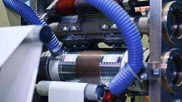 Enterprise for the production of diapers. Spinning shafts rotate and move the white layer between the gears of machine. Mechanism at work close up. video