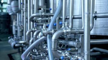 Numerous pipes crossing with each other at modern milk factory enterprise. Pipelines with valves and faucets. Close up with gradual distancing. video