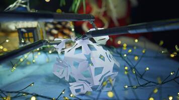 Robotic arms of high-precision surgery equipment hold the paper snowflake and cut little pieces off. Blurred Christmas decorations and lights at the backdrop. Close up. video