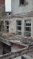 Aerial view of abandoned industrial buildings. Abandoned factory halls with broken glass on windows. Vertical video