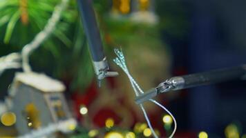 Tiny forceps of a medical surgical robot arms make a knot on the thread. Precise moves of a pair of pincers in dealing with little things close up. Christmas decorations at the background. video