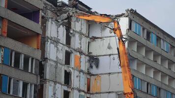 Top floors destruction by the hydraulic claw of excavator. Demolition of old house building for new construction by excavator bucket. View from the below. video