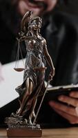 Statue of Justice with scales and a lawyer working on a laptop. Legal consultations and decision-making using modern technology for efficient legal solutions. Vertical video