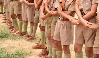 A group of children in khaki uniforms stand in a line photo