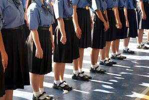 A group of girls in school uniforms stand in a line photo