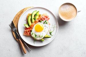 Breakfast toast with fried egg, bacon and avocado served with coffee photo