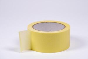 Roll of yellow masking tape on a plain background ready for use photo