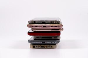 Collection of old mobile phones stacked in disarray on a clean surface photo