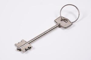 Large vintage key on a keyring resting on a plain background photo
