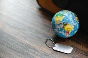 Earth Globe and Dog Tag on wood pattern work desk and soft sunlight background,World and map of Americas,Dog Tag empty,Desktop equipment,Concept of Travel and Work,Top view with copy space,Earth map. photo
