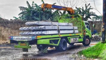 Bekasi, Indonesia on October 7, 2023. A small flat bed truck is transporting a pile of square pile or minipile material.. photo