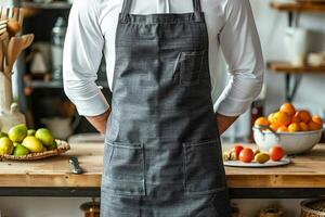 A chef wearing a dark gray linen-cotton apron stands in front of kitchen counter photo