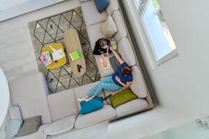 Top View of Mother and Daughter Enjoying a Fun Board Game on the Couch at Home photo