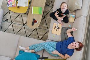 Top View of Mother and Daughter Enjoying a Fun Board Game on the Couch at Home photo
