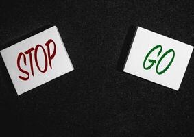 Two sticky notes on a black background with Stop and go written on it. photo