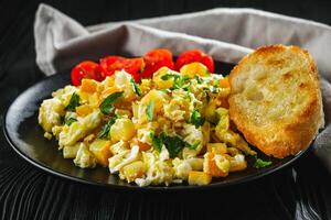 tasty scrambled eggs with zucchini on a black rustic rustic background photo