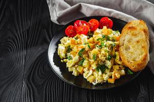tasty scrambled eggs with zucchini on a black rustic rustic background photo