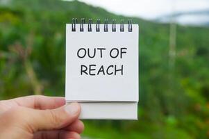 Out of Reach text on white notepad with nature background. Out of office concept photo