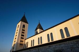 Beautiful Saint James church architecture with two steeples and a clear blue sky in the background, highlighting a serene and religious atmosphere in a tranquil setting in Medjugorje. photo