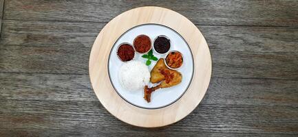 Ayam ungkep bumbu kuning or boiled chicken with curry seasoning and coconut water. Served with varian sambal or hot chili sauce. Ready to fried photo