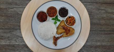 Ayam ungkep bumbu kuning or boiled chicken with curry seasoning and coconut water. Served with varian sambal or hot chili sauce. Ready to fried photo