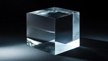 A glass cube contrasts with a black background, showcasing reflections of its surroundings. photo