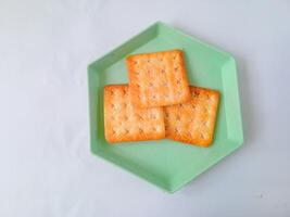 Sugar coated biscuits, also known as malkist, sweet and crispy. on a green hexagon plate isolate on white. snack concept photo