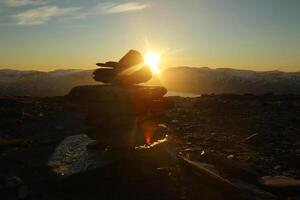 Midnight sun seen from the peak of Nuolja in Northern Sweden, with defocused cairn photo