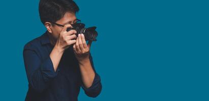 Photographer with a camera. Tomboy's holding the digital camera while standing on a blue background photo