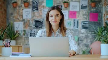 Portrait of a young,stylish Caucasian female manager sitting at her desk and using a laptop computer in a modern,colorful office environment. photo