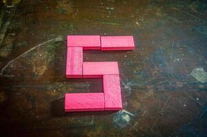 Red wooden blocks arranged in the shape of the number five on a rustic wooden surface. Perfect for educational, numerical, or creative concepts photo