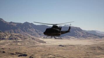 A helicopter flying over a desert landscape with mountains in the background video