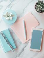 Desk setup with pastel stationery and phone on marble surface photo