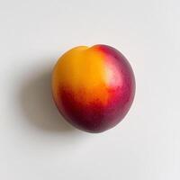 A single red and yellow peach on a white surface photo