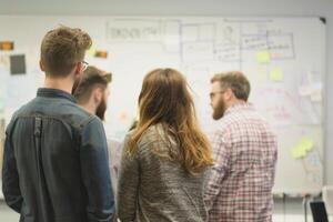 They are looking at the board and discussing the ideas on it photo