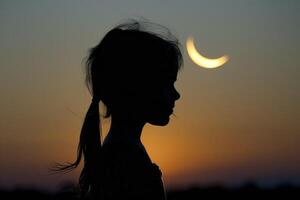 Silhouette of a girl with a crescent moon in the background photo