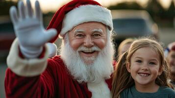 A man in a santa suit waving to a little girl photo