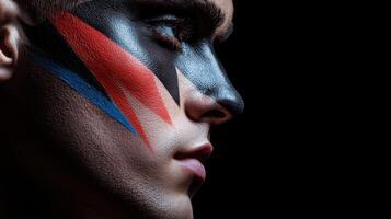 A man with a face painted with a red, blue and white stripe photo