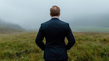 A man in a suit stands in a field of grass photo