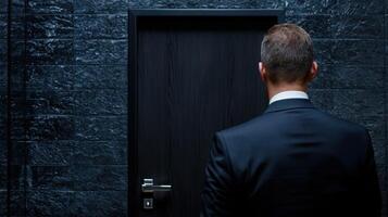 A man in a suit standing in front of a door photo